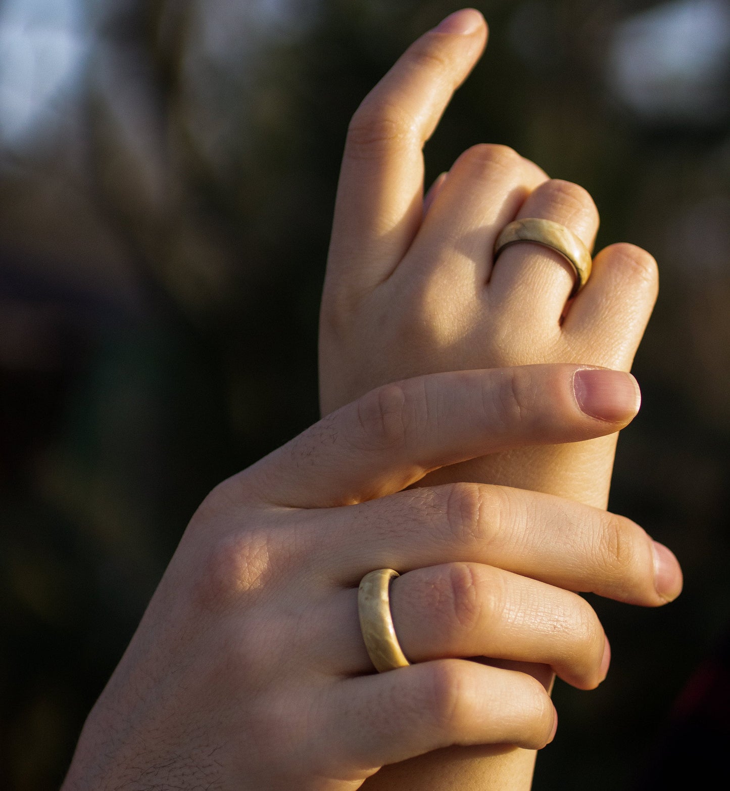 Hands intertwined wearing Maple Wood Rings with Stainless Steel Core by Andrwood, perfect for gay, lesbian, or young couples.