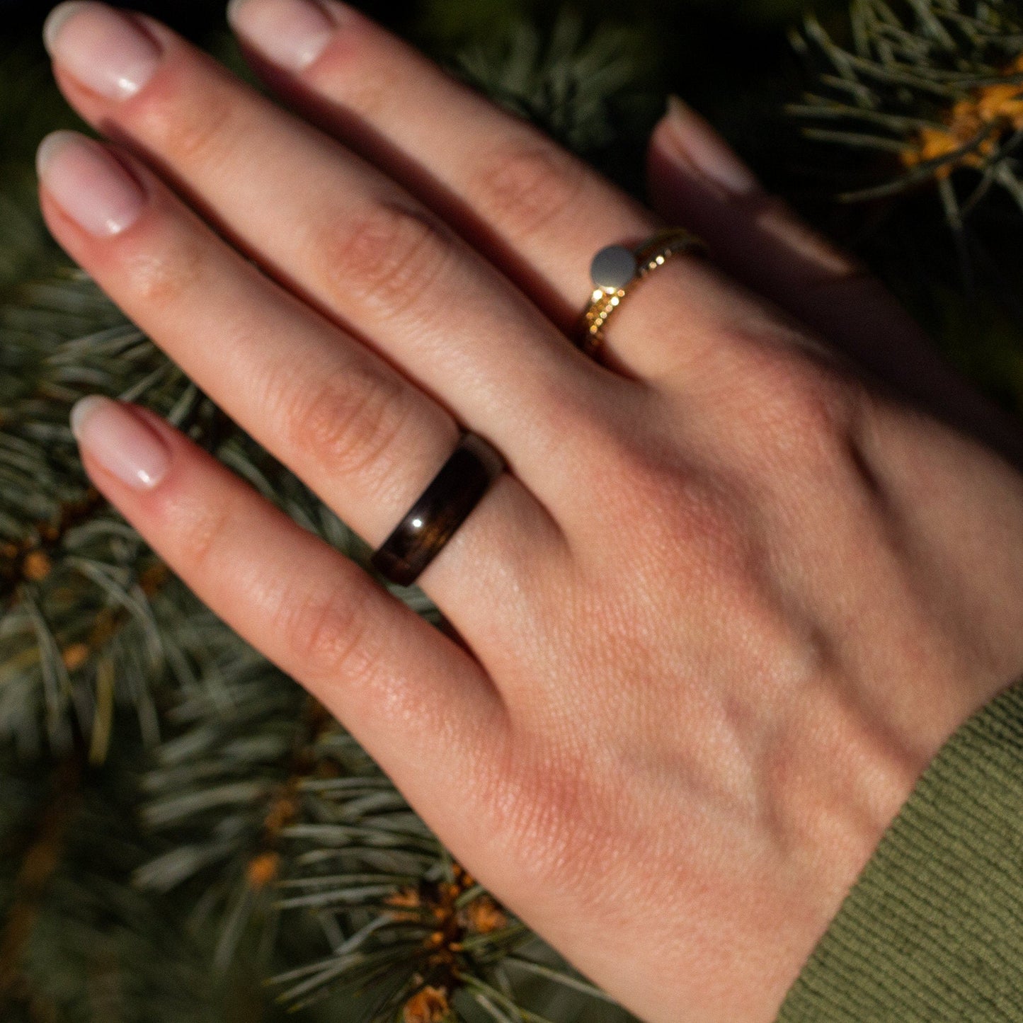 Minimalist ebony wood ring worn on a woman's hand, paired with a gold ring, perfect as a promise or anniversary gift.