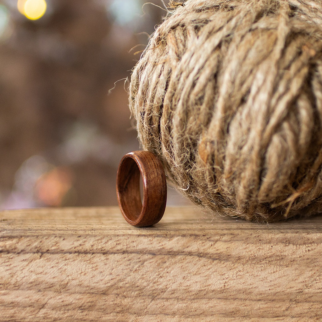 Makore ring placed beside rustic jute twine, styled on wood with soft bokeh in the background.