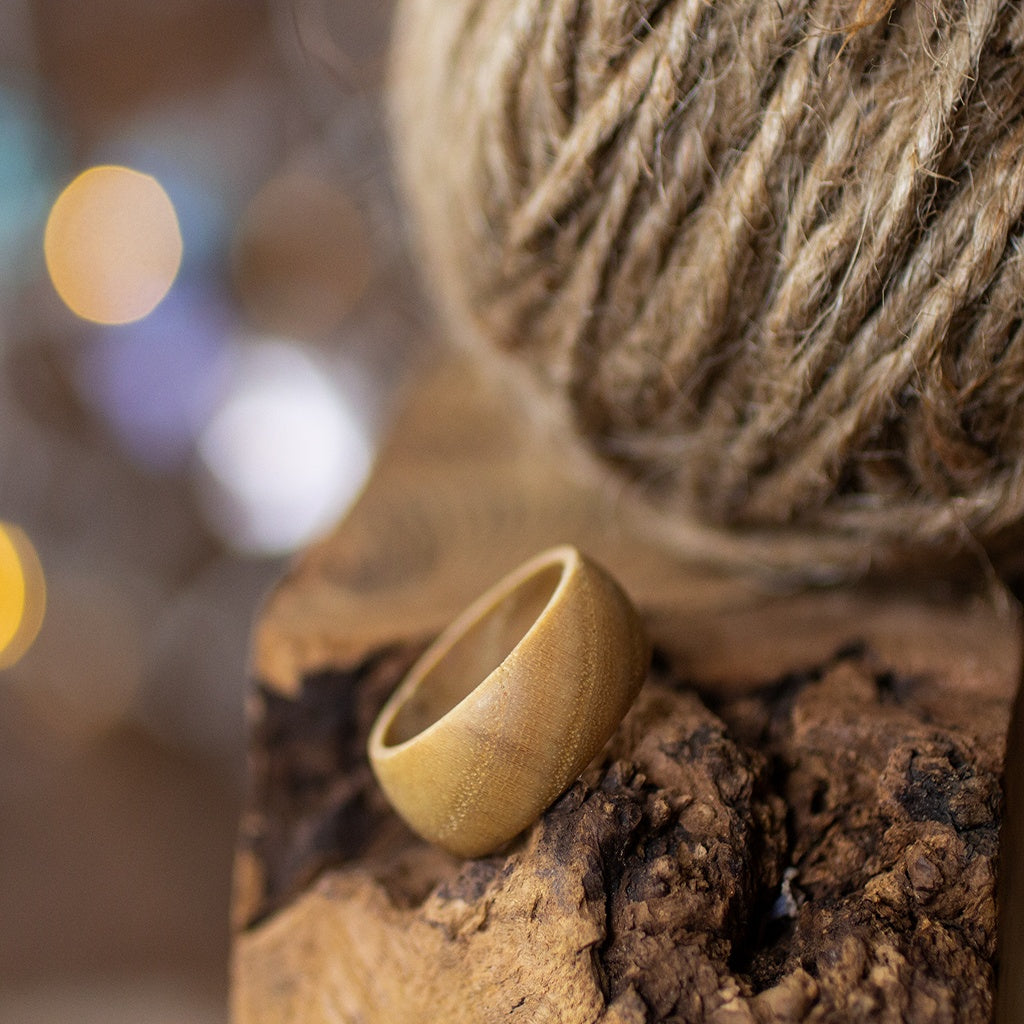 Matte ash ring leaning near rustic twine ball, styled on raw wood surface with gentle background blur.