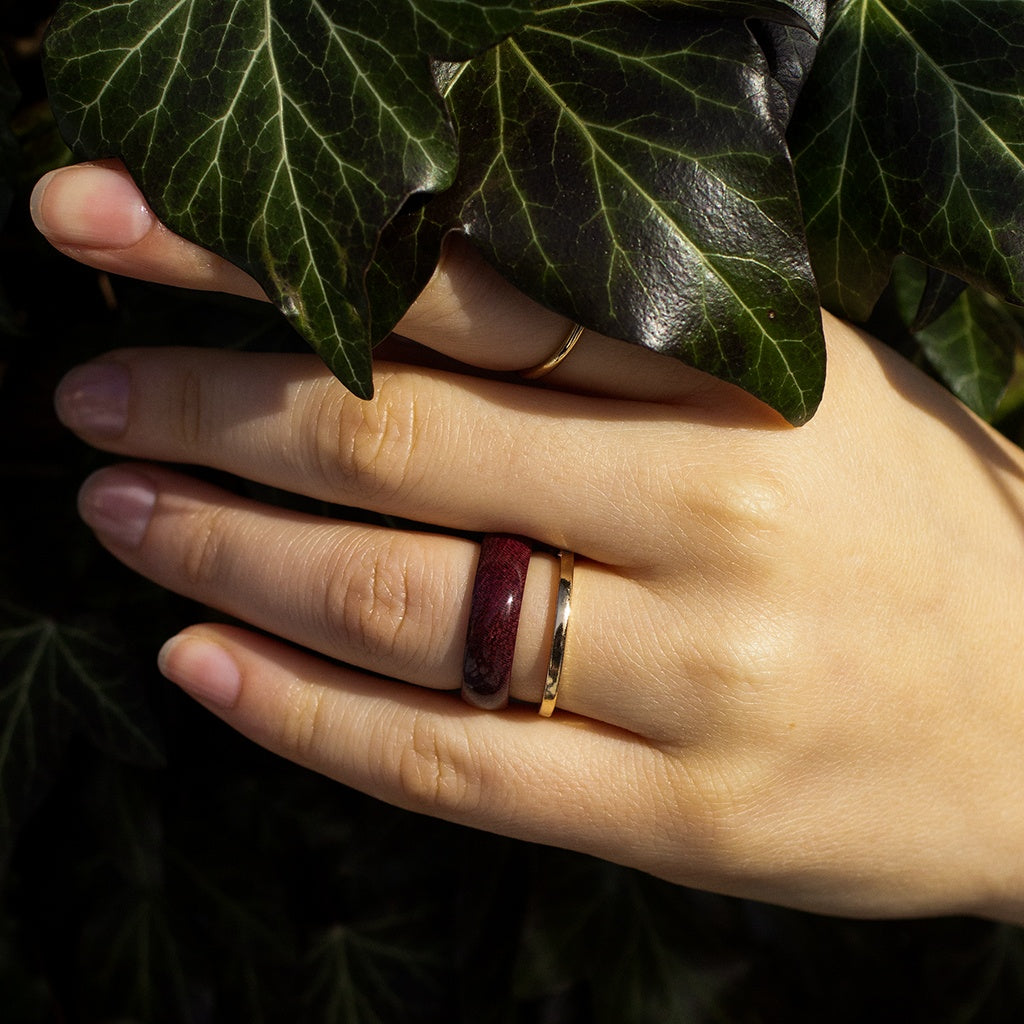 Woman’s hand with Purpleheart ring, styled with delicate gold accent ring in natural setting.
