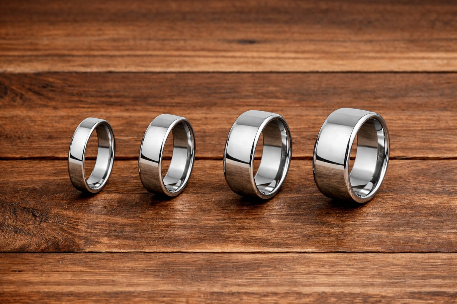 Comparison of men’s ring widths from narrow to wide on a wooden surface