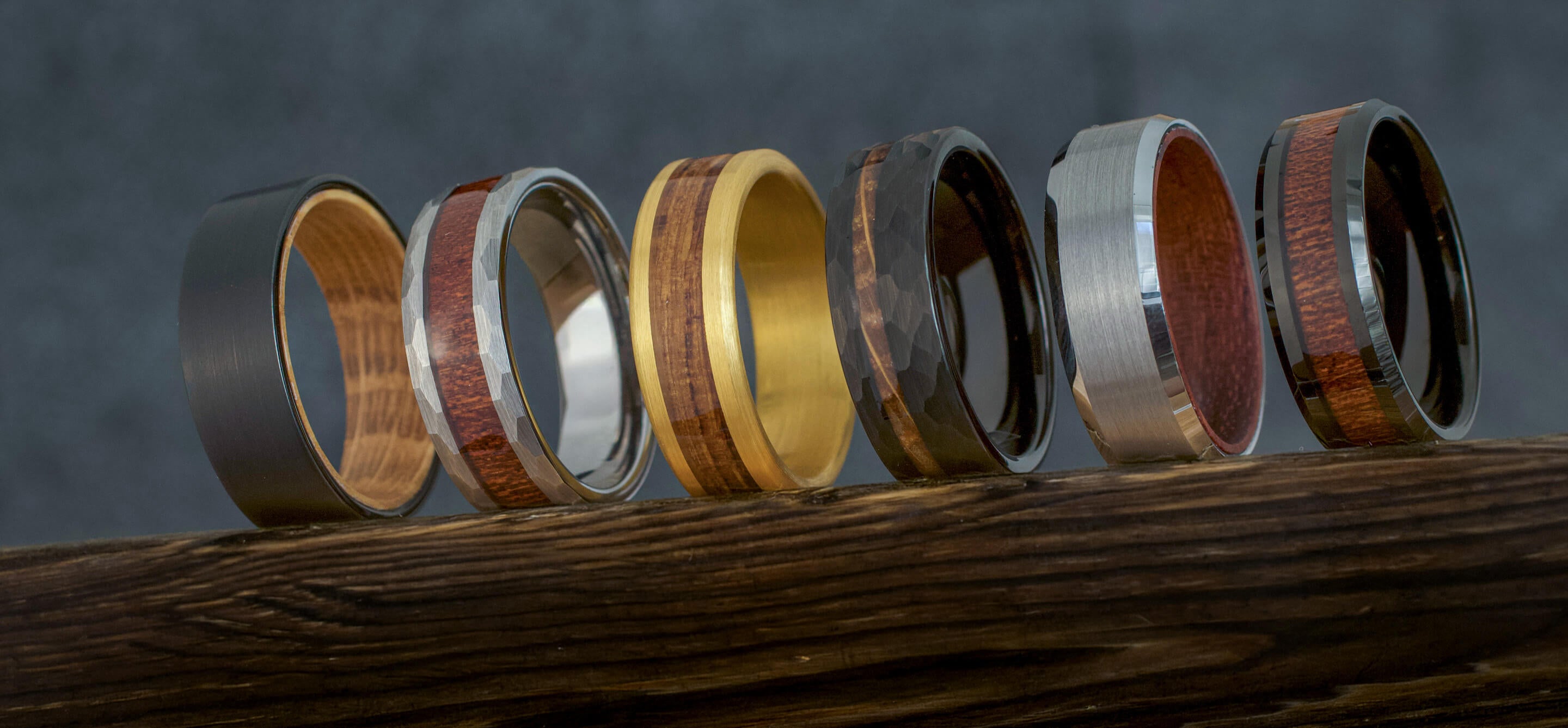 Set of tungsten rings with wood accents on a wooden surface