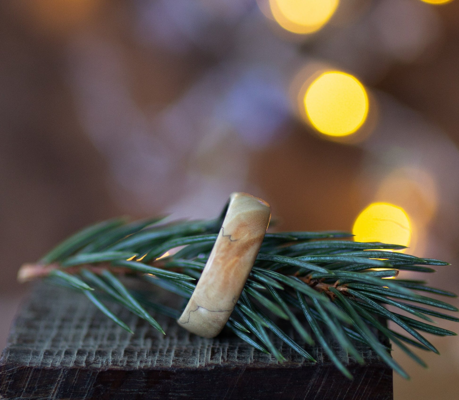 Andrwood Maple Wood Ring with Stainless Steel Core resting on pine branch, ideal for nature-inspired wedding or engagement rings.