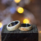 Maple Wood Ring with Stainless Steel Core by Andrwood displayed on rustic wood block, showcasing natural grain and polished finish.
