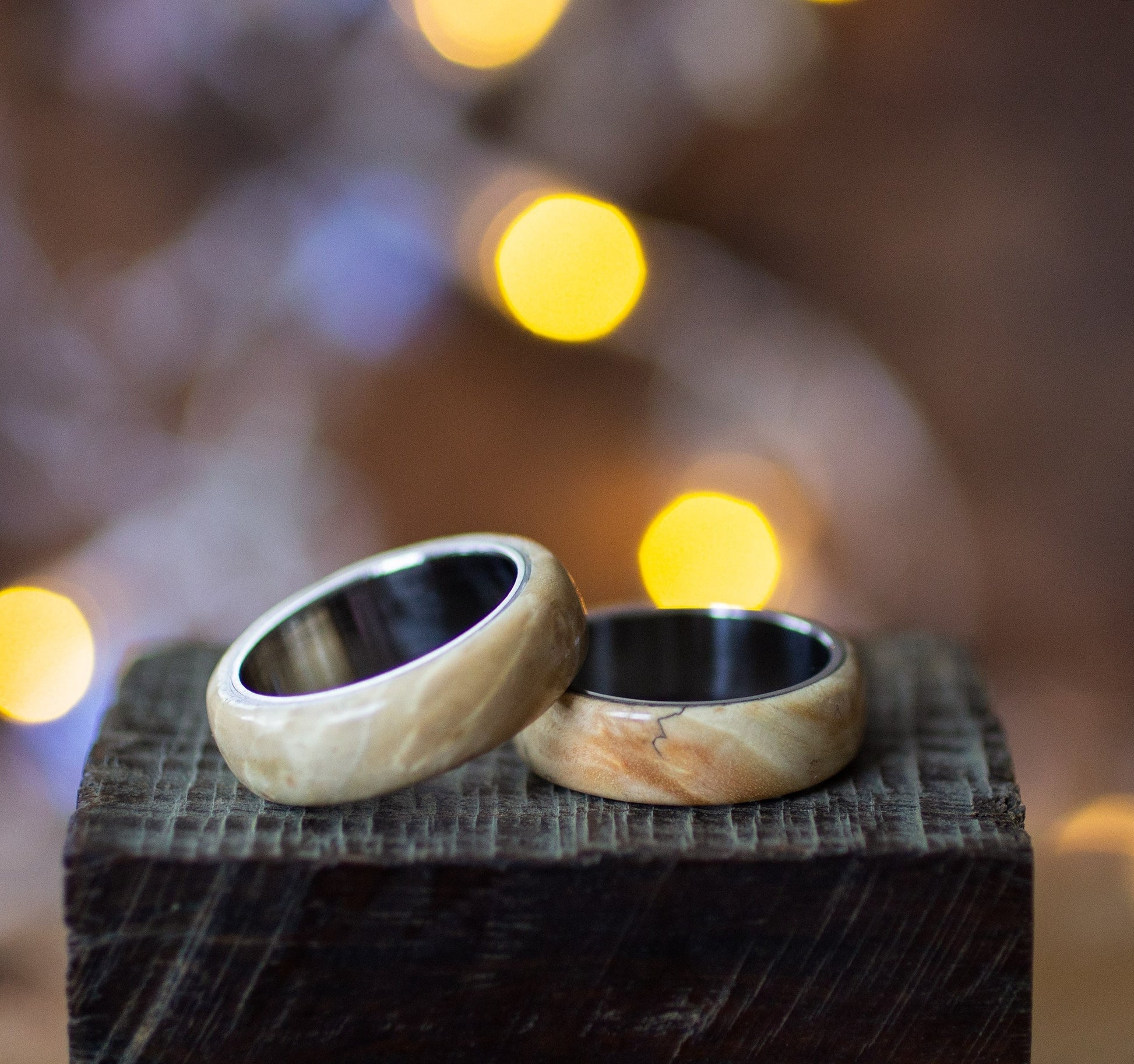 Maple Wood Ring with Stainless Steel Core by Andrwood displayed on rustic wood block, showcasing natural grain and polished finish.