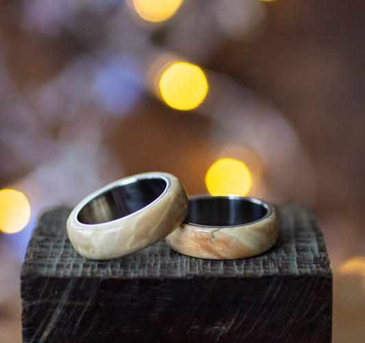 Maple Wood Ring with Stainless Steel Core by Andrwood displayed on rustic wood block, showcasing natural grain and polished finish.
