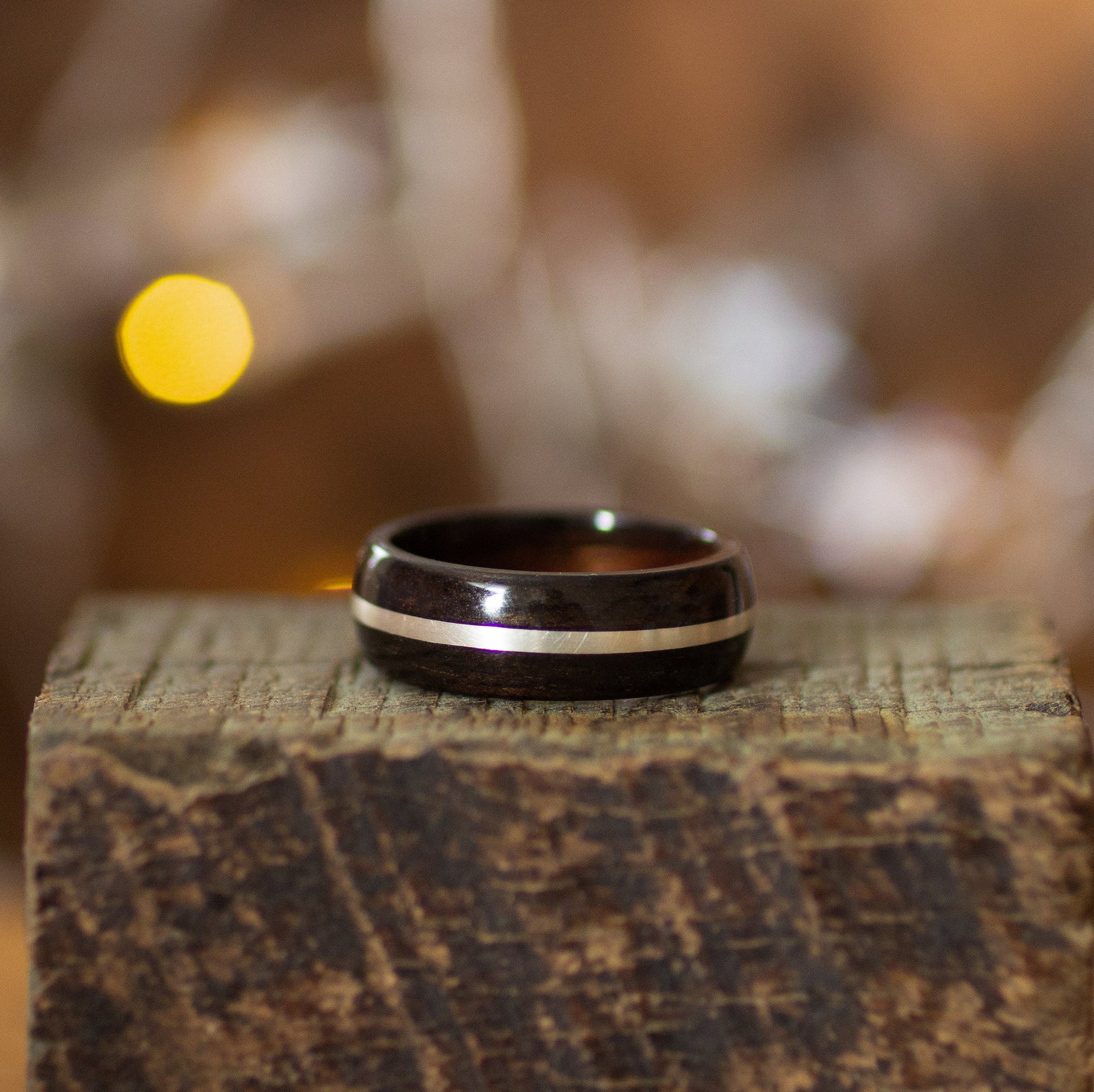 Close-up of handcrafted Ebony Wood Ring with Silver Inlay by Andrwood, highlighting the elegant contrast of dark wood and silver band.