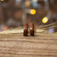 Makore wood rings paired together with dried grass accent, set against a softly lit wooden base.