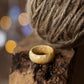 Glossy maple burl ring resting beside rustic twine ball, highlighting intricate burl grain patterns.