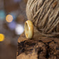 Side profile of maple burl ring with rich, natural figuring, styled with jute cord and warm tones.