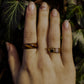 Hand wearing striped ash ring, fingers resting on ivy leaves in natural light.