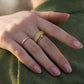 Hands wearing maple burl ring paired with delicate gold band, relaxed pose in warm ambient setting.